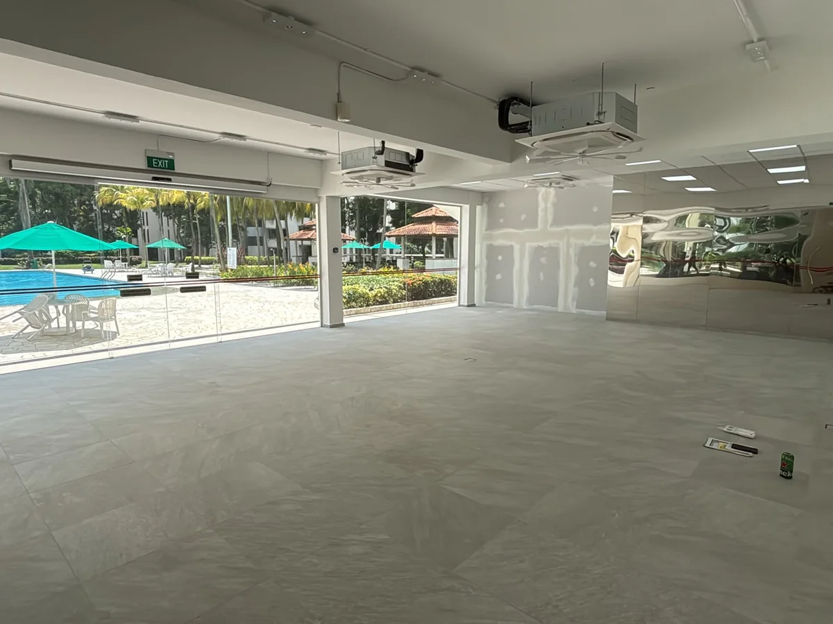 Empty shop unit with bare floor and glass frontage looking onto a swimming pool, before Casa Furnishing installed the cafe furniture